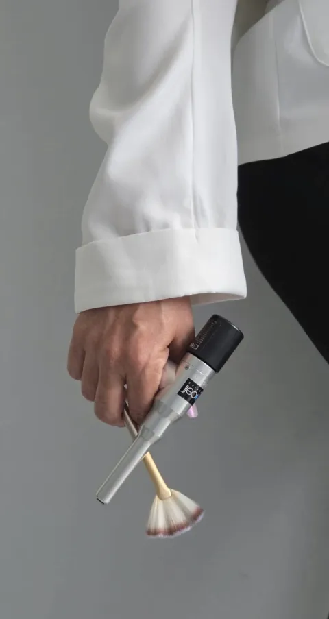 Mano con un dispositivo de microcanalización y una brocha para tratamiento facial